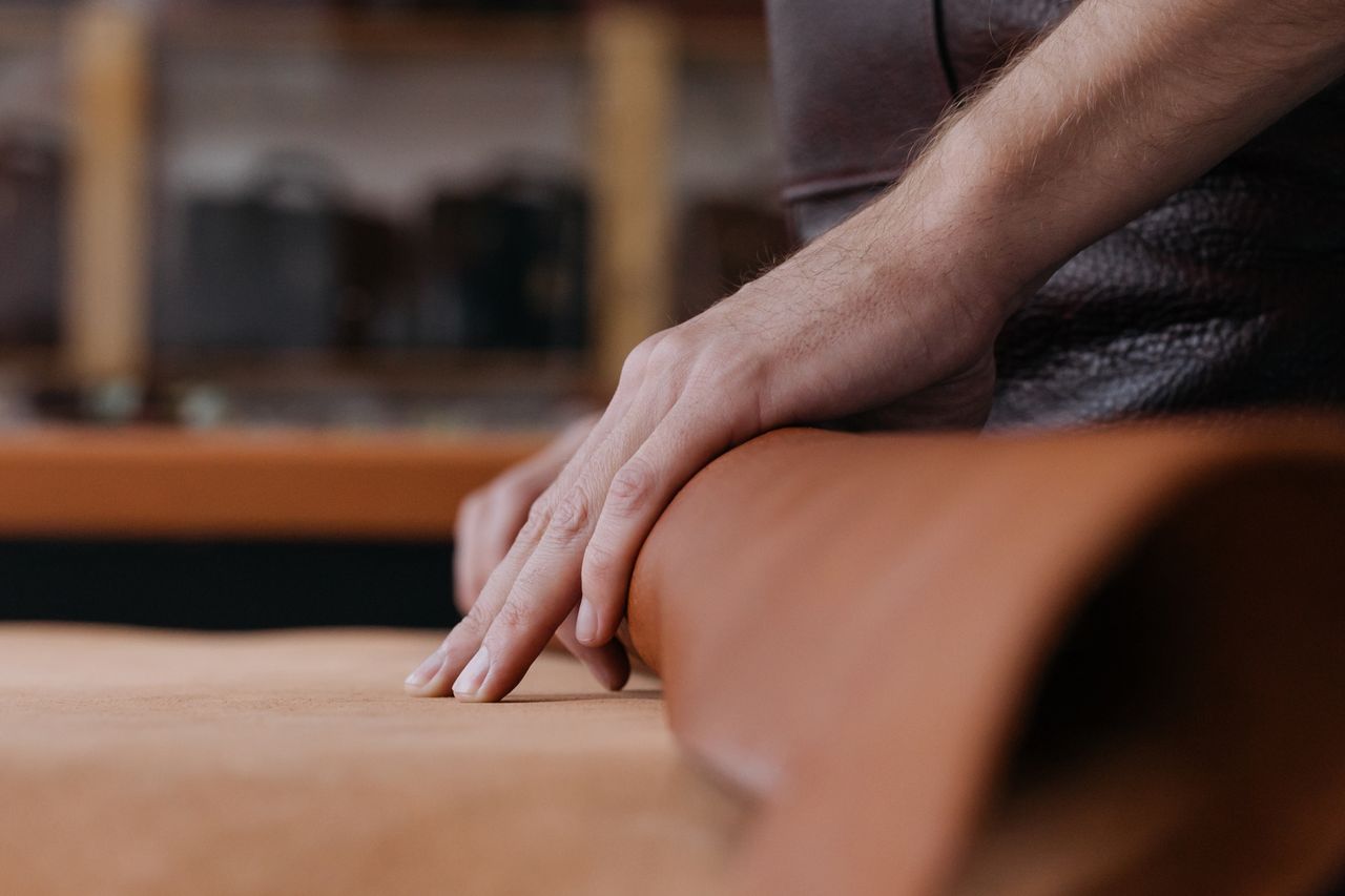 Crafting Captivating Headlines: Your awesome post title goes here Close-up of hands working with leather in a workshop, emphasizing craftsmanship and detail.